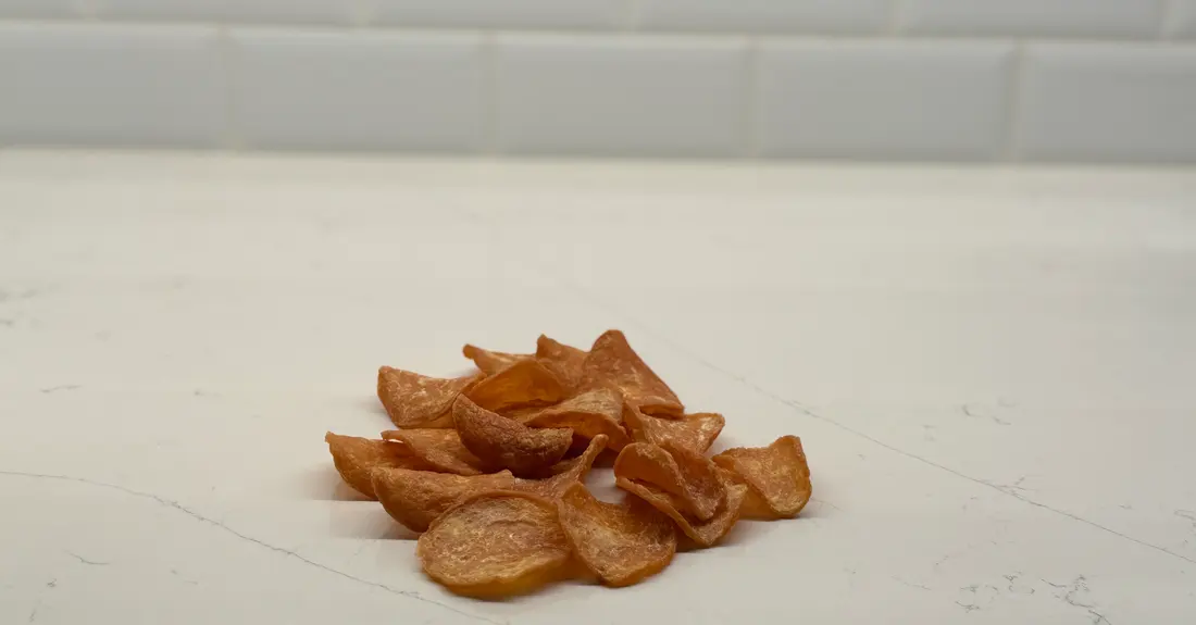 A small pile of crisp dehydrated chicken chips on a kitchen counter